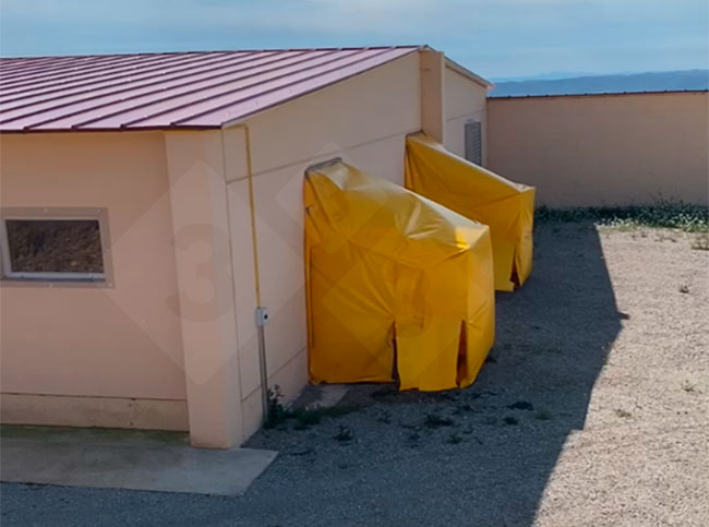 Foto 2. Una struttura di plastica &egrave; stata posizionata sui ventilatori di estrazione dell'aria dell'edificio N2 per deviare l'aria in uscita verso il pavimento, dove sono state collocate grandi vaschette contenenti disinfettante virucida.
